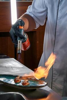 A Culinary Artist Uses a Torch to Create a Flamboyant Dish with Succulent Ingredients and an Impressive Flame Display for Gastronomic Spectacle photo