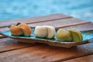 A Colorful Display of Traditional Japanese Mochi on a Ceramics Plate by the Seaside, Showcasing Unique Flavors and Textures in a Natural Setting photo