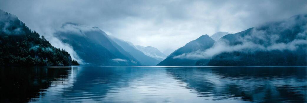 Serene Reflection of Misty Mountains on Calm Water Surface Under Overcast Sky in Remote Wilderness Setting photo