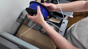 une la personne ensembles en haut une 3d imprimante avec bleu filament, mettant en valeur moderne La technologie et innovation dans une atelier réglage video