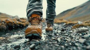 un persona caminando en rocoso sendero con su pies en el suciedad. el persona es vistiendo botas y tiene un mochila en. concepto de aventuras y exploración foto