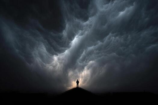 A man standing on top of a hill in front of a stormy sky photo