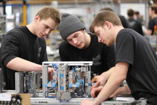 Three young men working on a machine in a factory photo