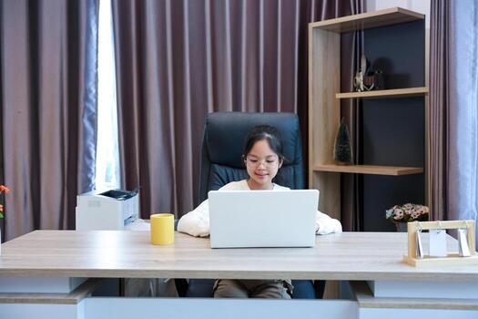 Young schoolgirl is doing her class homework assignment at home using laptop computer for education and study concept photo