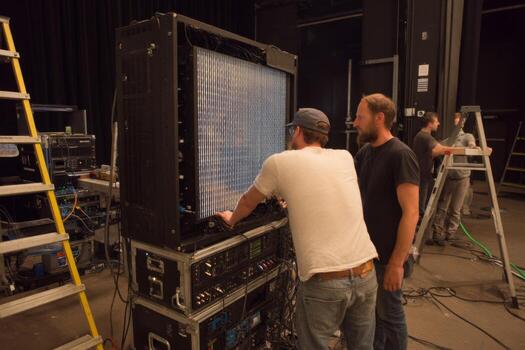 Two men working on a large screen in a large room photo