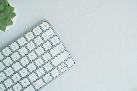 Minimalist top view of a modern wireless keyboard on white desk, symbolizing digital technology. photo