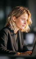 Focused businesswoman working on laptop in modern office photo