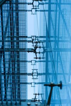 Geometric metal grid and framework with blue tones, viewed from below, creating a modern industrial pattern. Suitable for illustrating concepts of engineering, construction, architecture, or technology backgrounds. photo