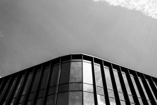 Contemporary architecture featuring a corner of a modern glass building with reflective windows and vertical lines. Suitable for illustrating urban development, business, or architectural design concepts. photo