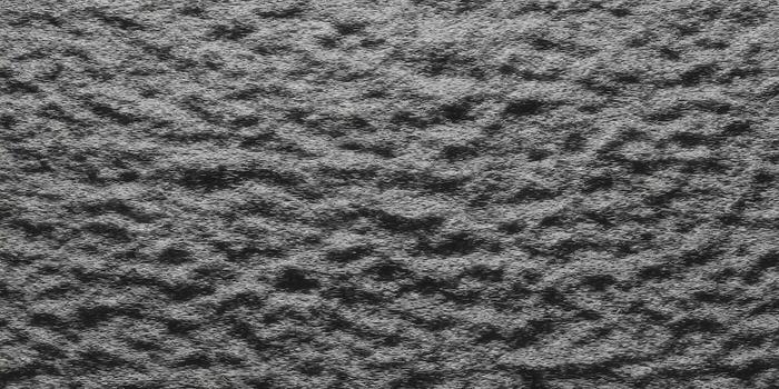 Detailed view of a textured, dark gray surface with a rough and uneven pattern. photo