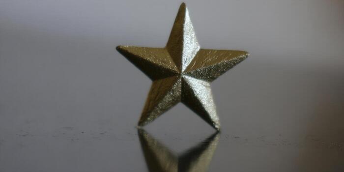 A golden star is brilliantly illuminated, showcasing its metallic shine and reflection. photo