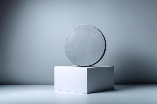 Grey circle object resting atop white cubic base on grey photo