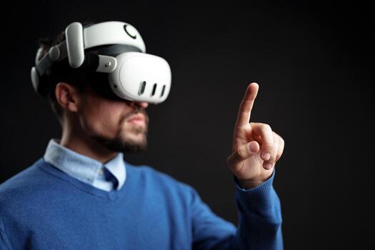 Man wearing virtual reality headset interacts with digital environment in a dark setting during an immersive gaming experience photo