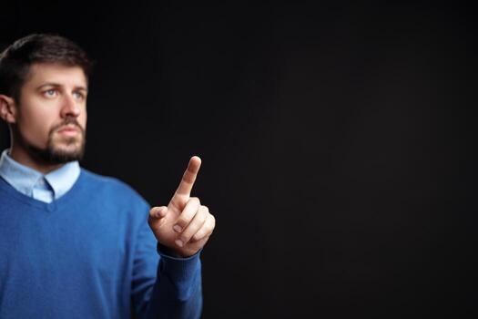 Man gestures with finger raised while expressing a point in a dark studio setting photo