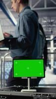 Vertical Close up of green screen tablet in front of data center engineers improving AI rigs. Server hub colleagues manage gear using mockup device to support artificial intelligence workloads, camera A video
