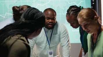 Diverse coworkers team participating in a late night briefing session, exchanging documents and reviewing finance updates. Aligning objectives through collaborative problem solving. Camera B. video