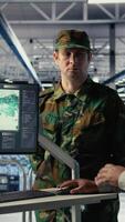 Vertical Team of military specialists in data center looking at world map on screen, coordinating mission zones. Army colleagues in server hub looking at global map to plan battlefield operations, camera A video