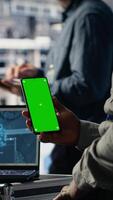 vertical técnico usando verde tela Smartphone dentro servidor cubo enquanto otimizando profundo Aprendendo sistemas tratamento tarefas. dados Centro trabalhador usa croma chave telefone, ajustando ai modelo parametros video