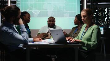 hembra supervisor y su personal miembros revisando eficiencia métrica dentro empresa, presentación proyecto visión durante un reunión. datos informes y previsiones para productividad. cámara una. video