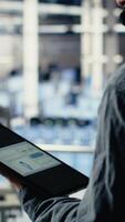 Vertical Data center technician using AI on tablet to help customers resolve website hosting problems. Server farm tech support professional helping users keep their online services running smoothly, camera B video