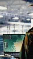 Vertical Military engineer in data center tracking satellite coordinates using laptop interface. Soldier in server room analyzing reconnaissance data through satellite imaging systems, camera B video