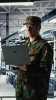 Vertical Army soldier in server farm uses artificial intelligence program on laptop to review reconnaissance information. Military data center worker uses deep learning to plan mission, camera A video