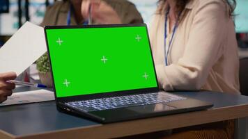 Team of businesswomen creates a strategy next to chroma key display with big TV monitor open and planning documents on the table. Showcasing business operations efficiency. Camera B. video