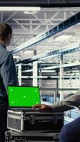 vertical eso compañeros de trabajo monitores servidor granja actividad utilizando aislado pantalla ordenador portátil. datos centrar ingenieros revisión aparejos pruebas resultados en croma llave cuaderno a garantizar sistemas son trabajando correctamente, cámara un video