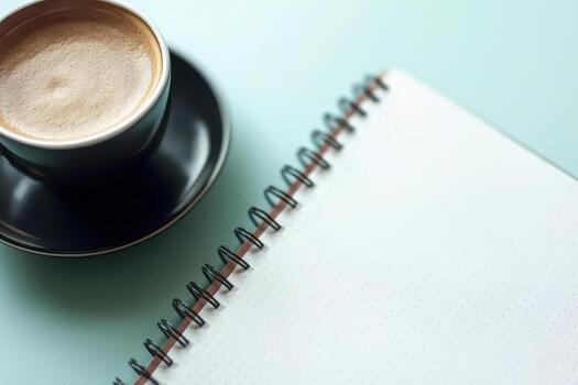 Coffee cup with notebook on plain turquoise background photo
