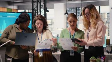 multietnico donne modulo un' potente squadra discutere attività commerciale strategia, analizzando prestazione dati su il computer portatile e documenti allineato in giro successo, progresso e condivisa obiettivi. telecamera b. video