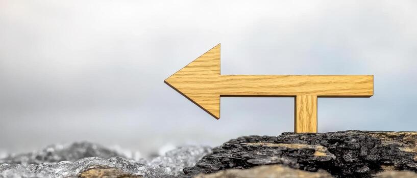 Wooden arrow sign pointing left on rocky surface with cloudy sky background photo