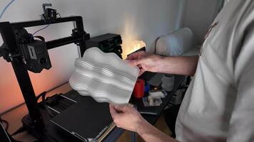 en person undersöker en 3d tryckt objekt i en verkstad, highlighting innovation, teknologi, och hantverk video