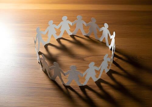 Paper chain people cutouts arranged in a circle on wooden surface symbolizing unity and teamwork, high-resolution image with crisp edges and natural lighting photo
