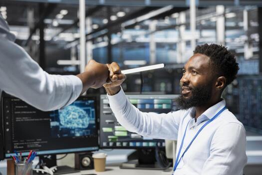 Server room worker greeting colleague, dong fist bump, using AI tools. Engineer saluting coworker, setting up data center equipment needed to run artificial intelligence and machine learning processes photo