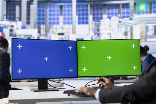 Photovoltaics facility employee reviews efficiency data on isolated screen computer monitors to improve production output. Solar panels plant expert identifying system errors using mockup PC display photo