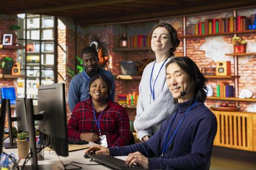 Portrait of joyful multiethnic call center agents in office providing step by step guidance to customers. Happy multiracial customer support workers at PC desk walking clients through solutions photo