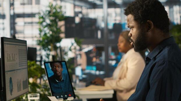 Manager chatting with worker in videoconference, setting goals for performance and company growth. Manager in teleconference business meeting with employee using tablet, camera A photo