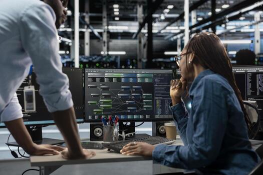 System administrators running node trees code and programming on PC, troubleshooting and upgrading server farm equipment designed to accommodate mainframes, networking racks and storage arrays photo