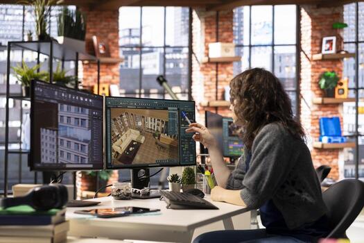 Female arranging virtual assets in a architectural software on dual monitors, creating a detailed 3D render of a floor plan. Woman uses the program for computer aided interior design. photo