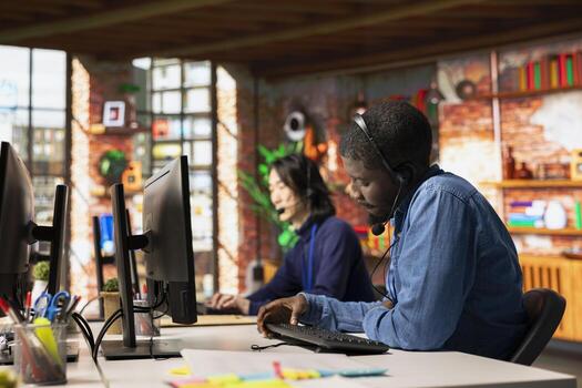 Call center staff member using remote access tools to connect to customer devices remotely for troubleshooting. African american customer center worker assisting users with installing software photo