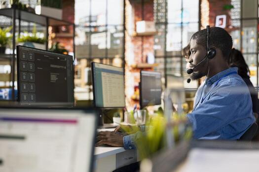 Call center worker using artificial intelligence chatbot to provide multilingual support to customers. African american customer support operator leveraging AI tools to translate clients interactions photo