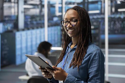 Smiling server hub IT specialist troubleshoots gear issues. Portrait of radiant data center system administrator using tablet to monitor equipment performance, identifying bottlenecks. photo