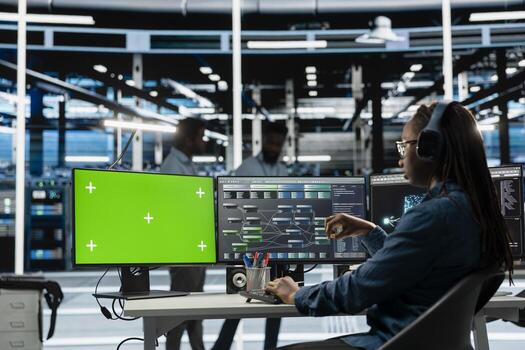 Woman in data center using green screen computer to check for server performance issues. IT expert at work in server room fixing errors slowing down hardware using chroma key PC photo