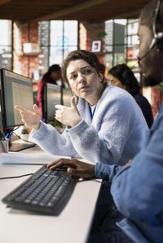 Customer service manager supervising man logging customer interactions in CSM system on computer. Call center supervisor overseeing employee using customer service management software on PC photo