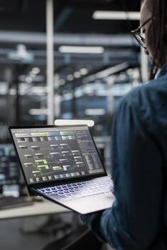Close up of data center admin using laptop to setup machine learning systems handling information. IT specialist using notebook device to train neural networks to improve server farm operations photo