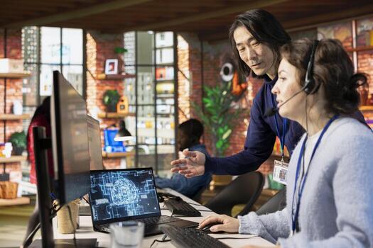 Call center onboarding specialist providing training to new agent on helpful AI tools. Manager in customer support department office providing support on how to use company AI software photo