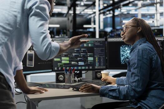 Server farm teamworking engineers doing brainstorming, looking at data analysis graph to reduce failures. Data center colleagues talking, working together using AI visualization dashboard photo