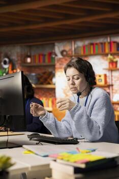 Call center agent in office helping customers solve their issues, addressing complaints. Woman in customer support workspace using headset mic to talk with clients, assisting with orders photo