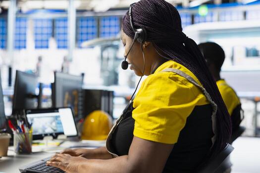 Black factory technician offers assistance from solar panel call center, managing help line requests for support and troubleshooting. Customer service assistant improves operations. photo