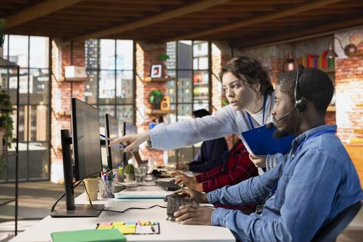 Customer service manager teaching new worker how to track support tickets in dedicated company software on computer. Call center supervisor shows african american intern how to create support tickets photo